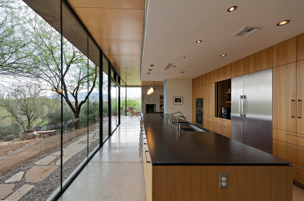 Kitchen - large modern galley concrete floor kitchen idea in Phoenix with an undermount sink, flat-panel cabinets, medium tone wood cabinets and stainless steel appliances