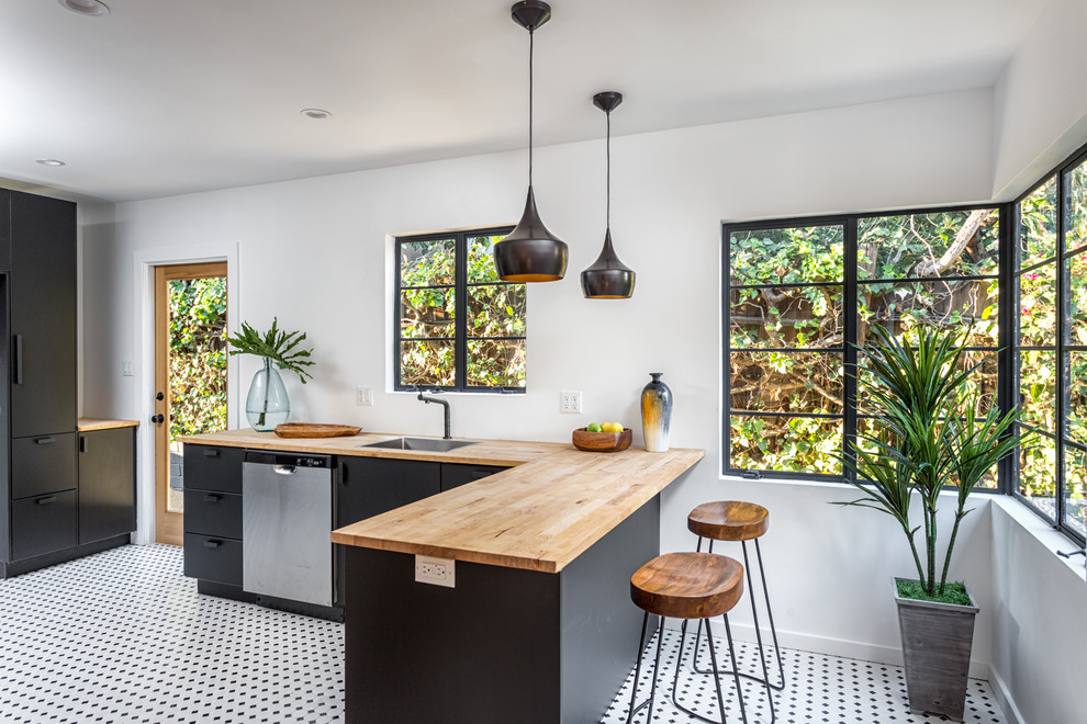 Zweizeilige Moderne Küche mit Unterbauwaschbecken, flächenbündigen Schrankfronten, schwarzen Schränken, Arbeitsplatte aus Holz, Küchenrückwand in Weiß, Kücheninsel und buntem Boden in Los Angeles