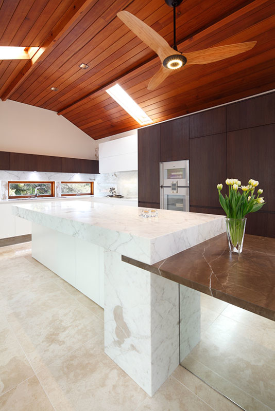 Example of a large minimalist single-wall travertine floor open concept kitchen design in Sydney with a single-bowl sink, flat-panel cabinets, dark wood cabinets, marble countertops, multicolored backsplash, mirror backsplash, stainless steel appliances and two islands