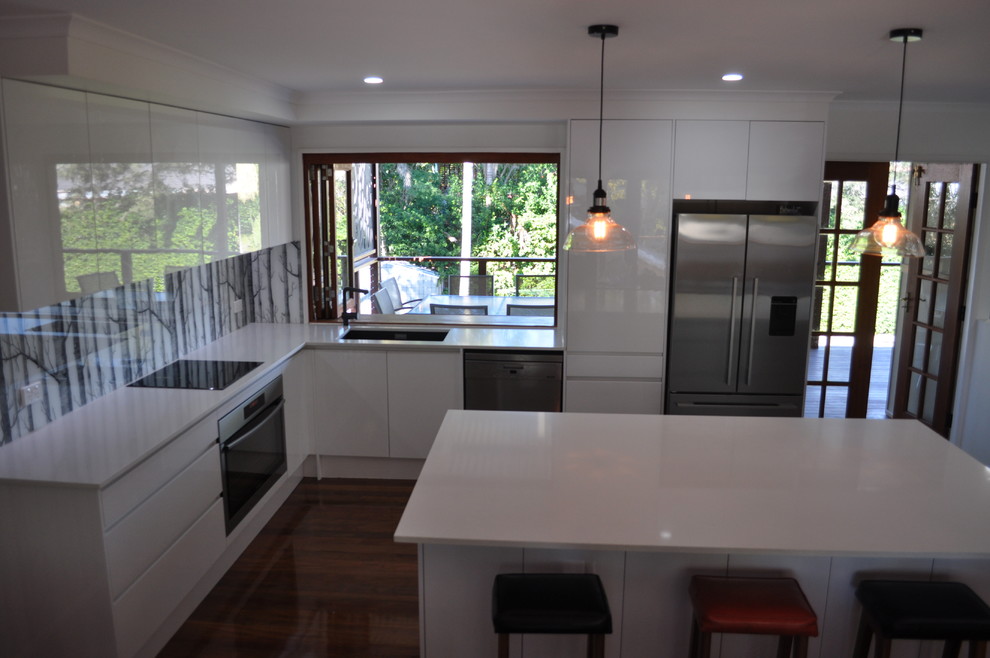 Exempel på ett mellanstort modernt kök, med en undermonterad diskho, släta luckor, vita skåp, bänkskiva i kvarts, flerfärgad stänkskydd, glaspanel som stänkskydd, rostfria vitvaror, mörkt trägolv och en köksö