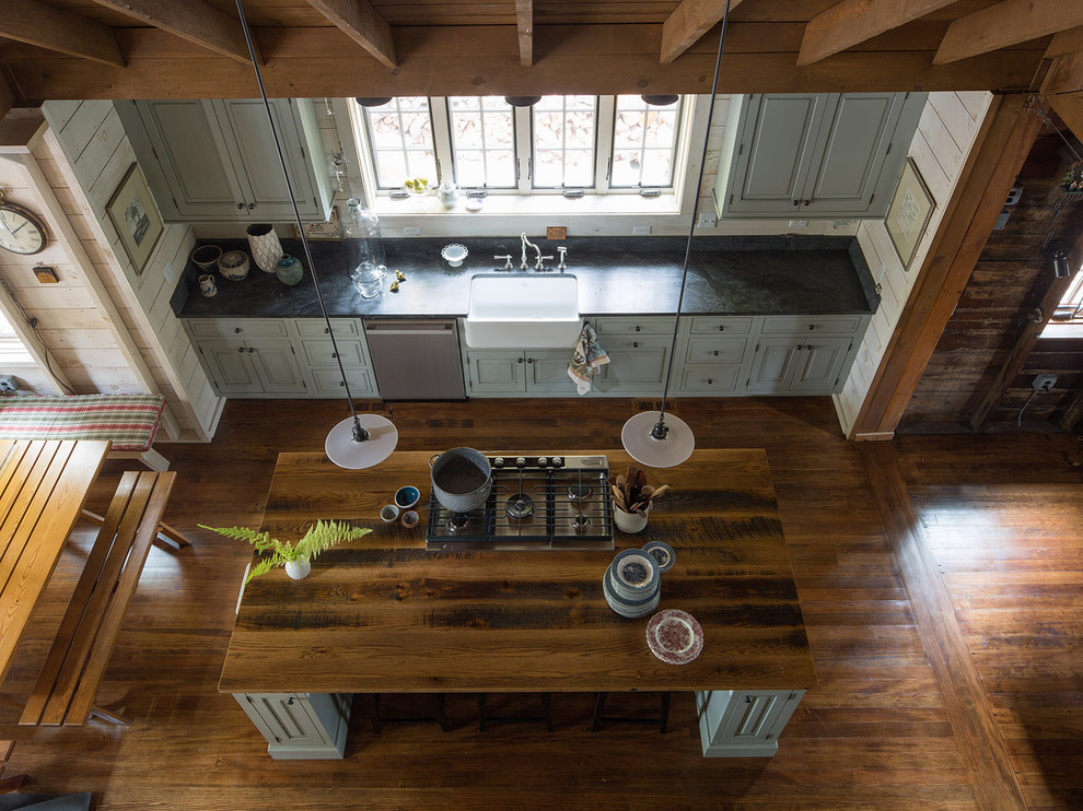 Inspiration for a mid-sized rustic galley medium tone wood floor eat-in kitchen remodel in New York with a farmhouse sink, raised-panel cabinets, blue cabinets, soapstone countertops, black backsplash, stone slab backsplash, stainless steel appliances and an island