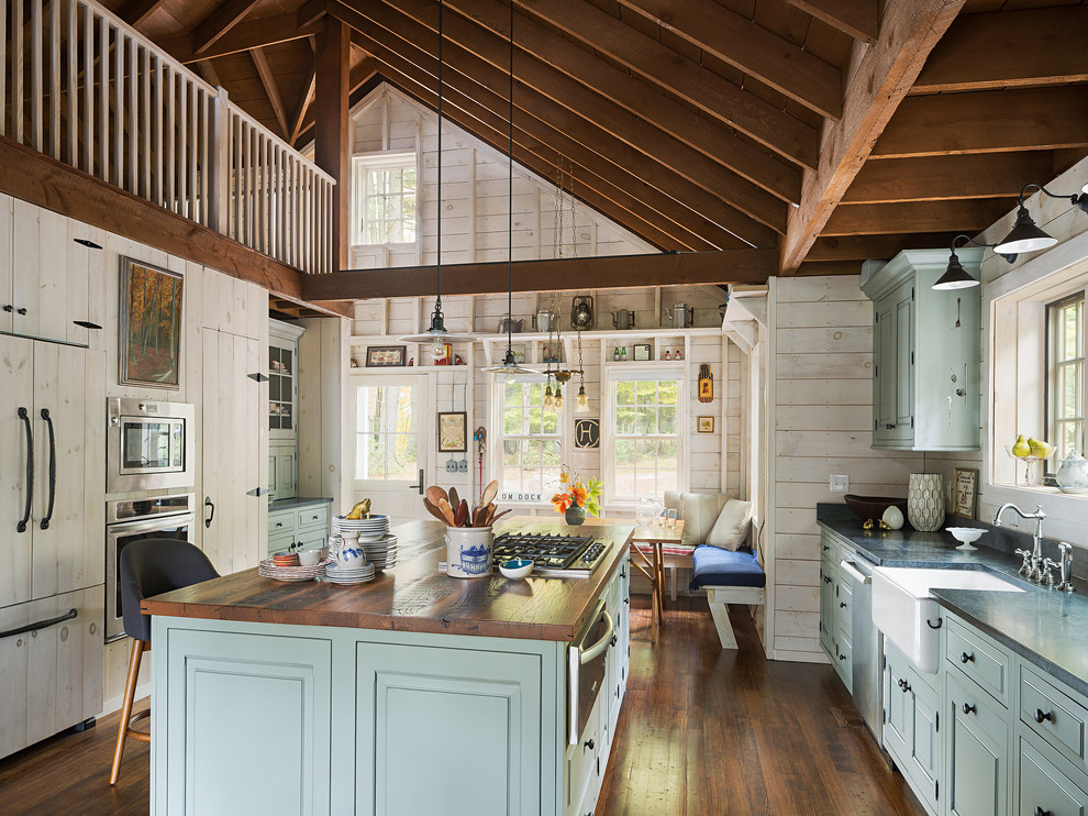 Example of a large mountain style dark wood floor eat-in kitchen design in New York with a farmhouse sink, raised-panel cabinets, blue cabinets, granite countertops, stainless steel appliances and an island