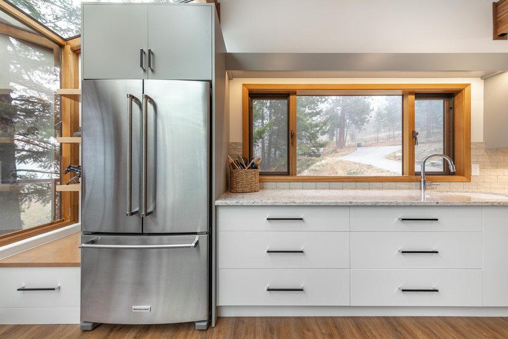 Immagine di una cucina minimal di medie dimensioni con lavello sottopiano, ante lisce, ante grigie, top in granito, paraspruzzi bianco, paraspruzzi con piastrelle diamantate e elettrodomestici in acciaio inossidabile