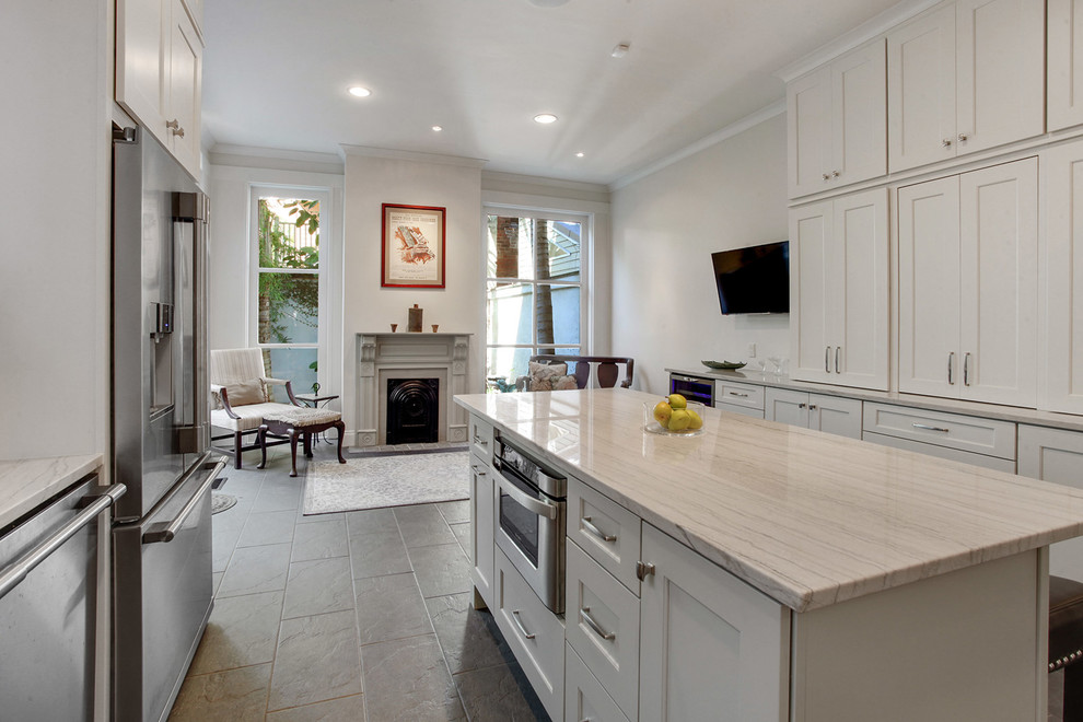 Inspiration for a large transitional l-shaped ceramic tile and brown floor kitchen remodel in New Orleans with white cabinets, quartzite countertops, stainless steel appliances, an island, an undermount sink, shaker cabinets, white backsplash, subway tile backsplash and white countertops