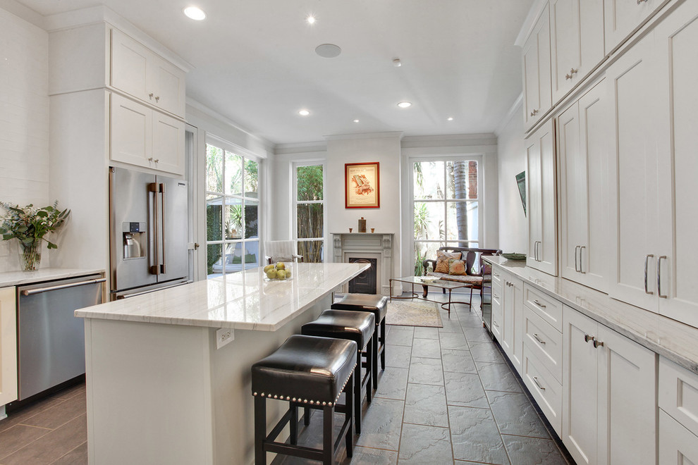 Kitchen - large transitional l-shaped ceramic tile and brown floor kitchen idea in New Orleans with an undermount sink, shaker cabinets, white cabinets, quartzite countertops, white backsplash, subway tile backsplash, stainless steel appliances, an island and white countertops