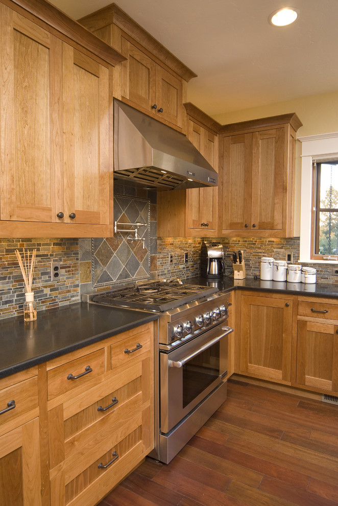Kitchen - traditional kitchen idea in Seattle with stainless steel appliances, slate backsplash and black countertops