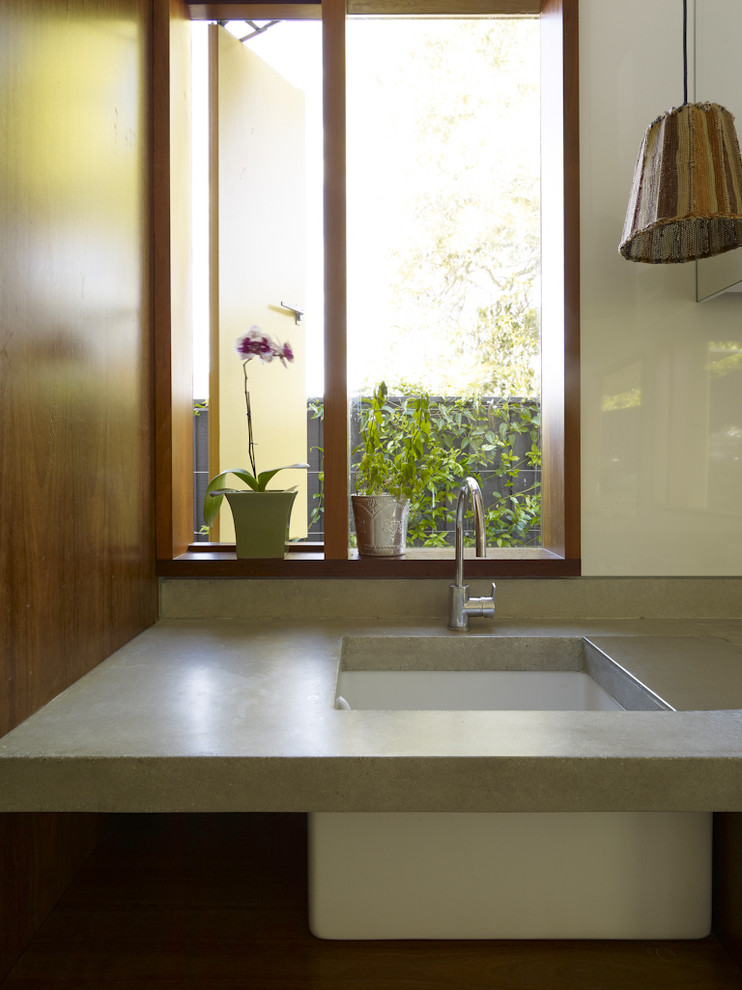 Immagine di una cucina minimal con lavello sottopiano, top in cemento, paraspruzzi bianco e elettrodomestici in acciaio inossidabile