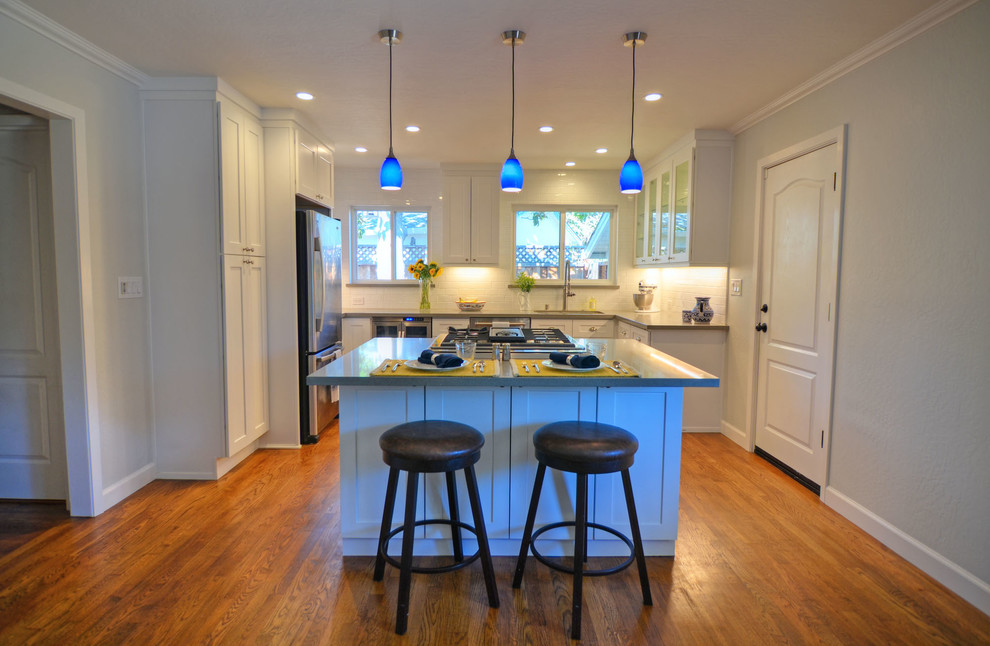 Small trendy u-shaped dark wood floor and brown floor eat-in kitchen photo in San Francisco with an undermount sink, shaker cabinets, white cabinets, quartz countertops, white backsplash, subway tile backsplash, stainless steel appliances and an island