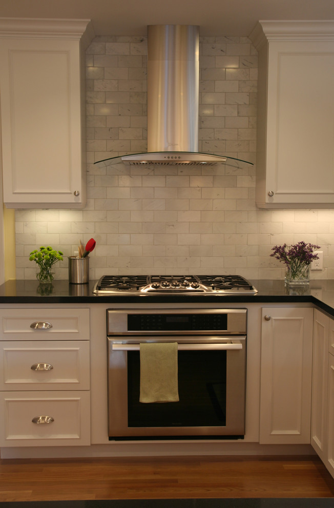 Bild på ett vintage kök, med rostfria vitvaror, luckor med infälld panel, vita skåp, stänkskydd i stenkakel och grått stänkskydd