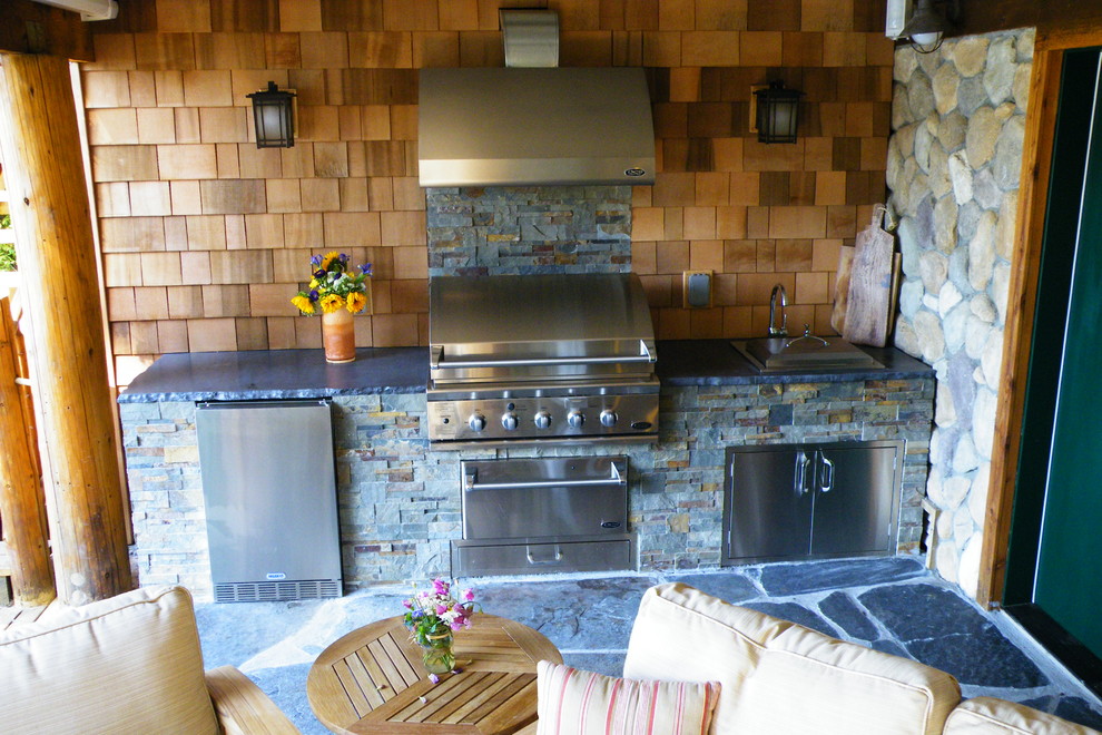 Rustik inredning av ett stort kök, med en nedsänkt diskho, bänkskiva i betong, rostfria vitvaror, skiffergolv och en köksö