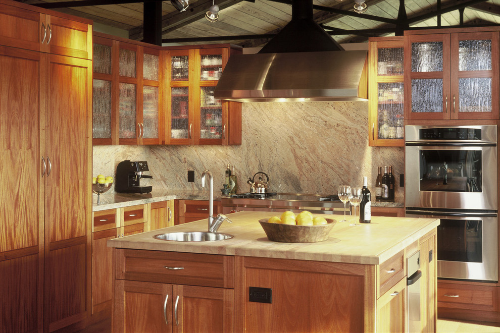 Urige Küche in L-Form mit Einbauwaschbecken, Rückwand aus Stein und Kücheninsel in Sonstige