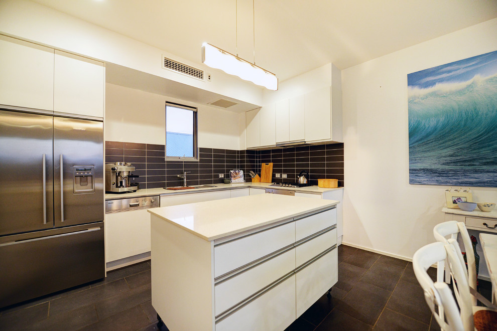 Photo of a medium sized contemporary l-shaped kitchen/diner in Sydney with a single-bowl sink, flat-panel cabinets, white cabinets, engineered stone countertops, black splashback, ceramic splashback, stainless steel appliances, ceramic flooring and an island.