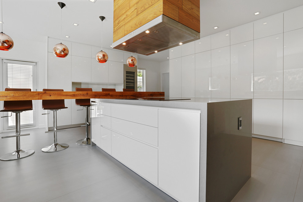 Foto di una cucina ad U design di medie dimensioni con lavello sottopiano, ante bianche, top in acciaio inossidabile, elettrodomestici in acciaio inossidabile, pavimento in cemento e penisola