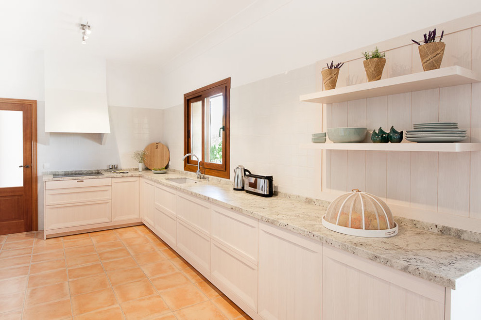 Nordisk inredning av ett avskilt, stort l-kök, med en enkel diskho, luckor med upphöjd panel, vita skåp, granitbänkskiva, vitt stänkskydd och klinkergolv i keramik