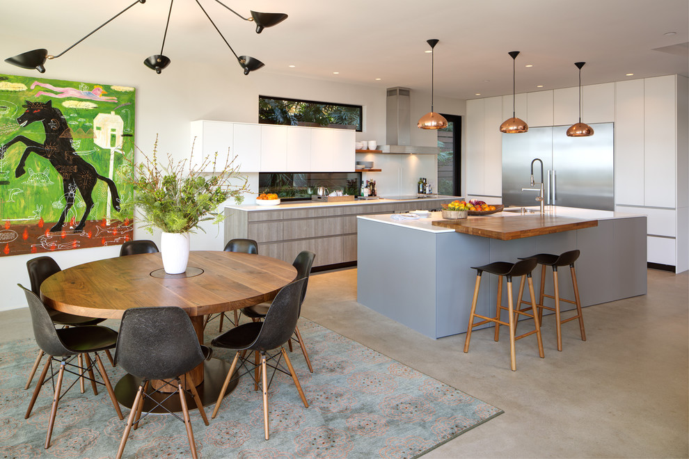 Zweizeilige, Mittelgroße Moderne Wohnküche mit Unterbauwaschbecken, flächenbündigen Schrankfronten, weißen Schränken, Mineralwerkstoff-Arbeitsplatte, Küchengeräten aus Edelstahl, Betonboden, Kücheninsel und grauem Boden in San Diego