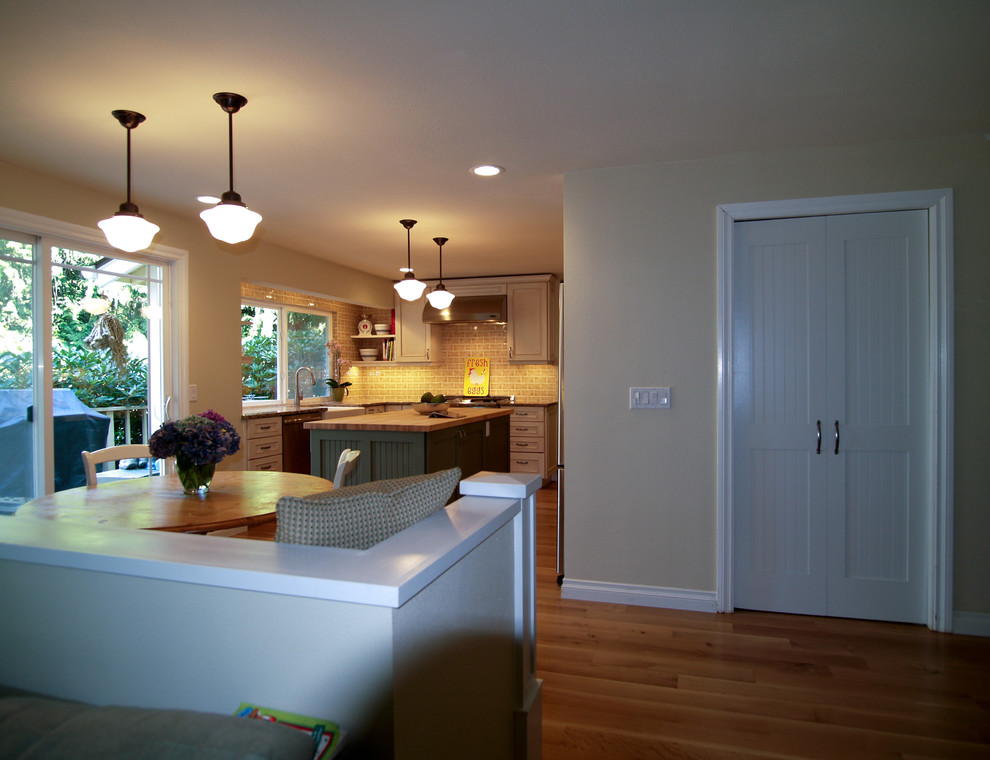 Exempel på ett mellanstort klassiskt beige beige kök, med en rustik diskho, luckor med infälld panel, gröna skåp, träbänkskiva, beige stänkskydd, stänkskydd i tunnelbanekakel, rostfria vitvaror, mellanmörkt trägolv, en köksö och beiget golv