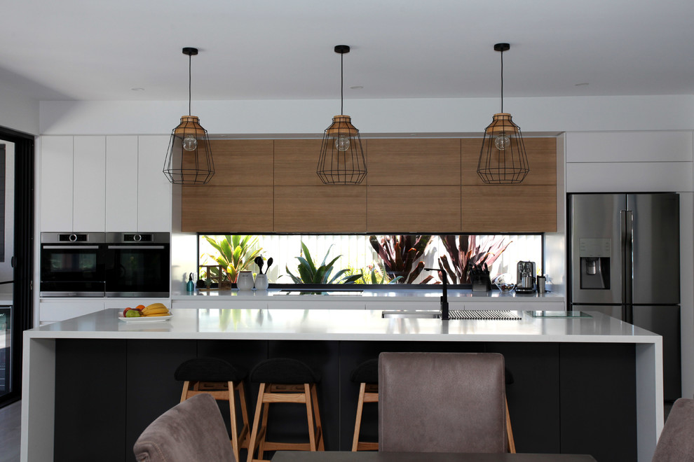Foto di una cucina stile marinaro con lavello sottopiano, ante lisce, ante in legno scuro, paraspruzzi a finestra, elettrodomestici in acciaio inossidabile e top bianco