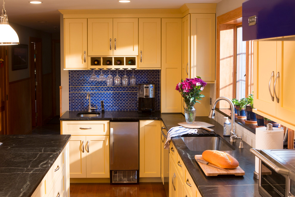 Mittelgroße Klassische Wohnküche in L-Form mit Schrankfronten im Shaker-Stil, gelben Schränken, Küchenrückwand in Blau, Rückwand aus Keramikfliesen, Küchengeräten aus Edelstahl, braunem Holzboden und Kücheninsel in Providence