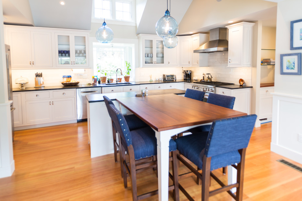 Large beach style medium tone wood floor eat-in kitchen photo in Boston with a drop-in sink, raised-panel cabinets, white cabinets, granite countertops, white backsplash, mosaic tile backsplash and an island