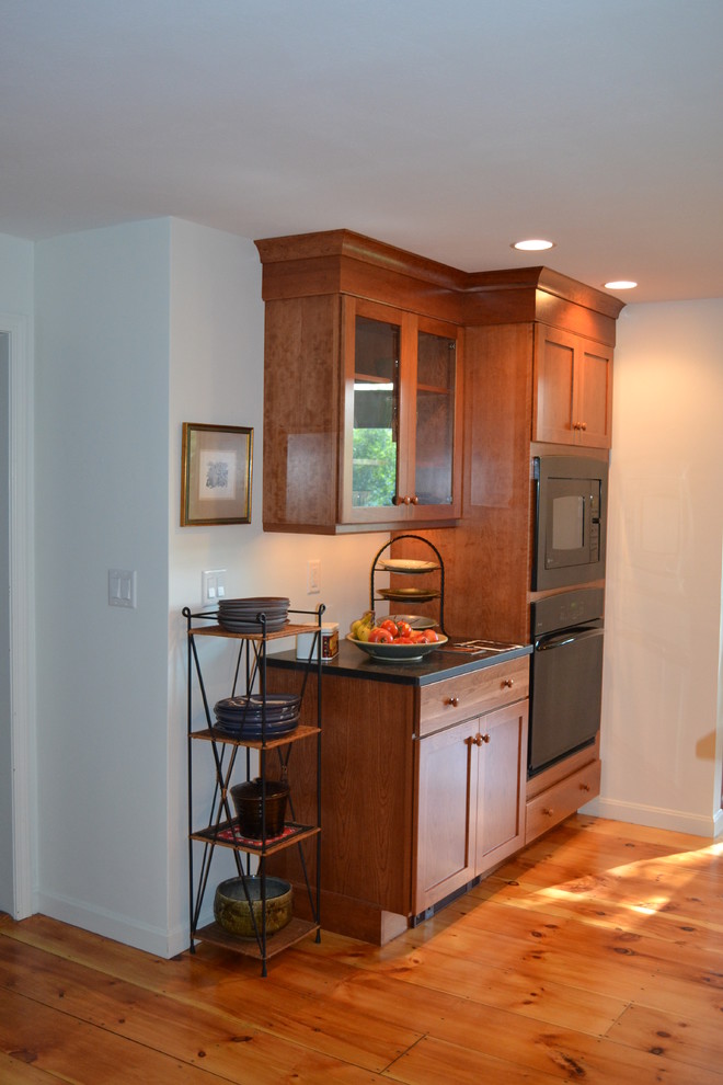 Large classic kitchen in Boston with a submerged sink, shaker cabinets, medium wood cabinets, granite worktops, black appliances and light hardwood flooring.