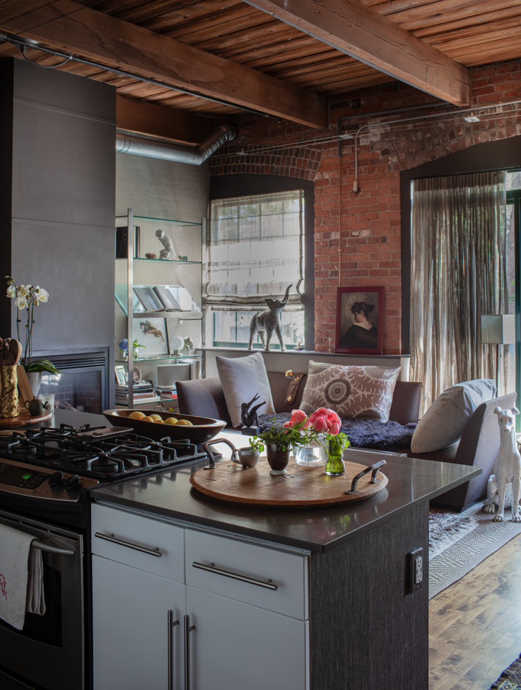 Medium sized bohemian l-shaped kitchen/diner in Boston with flat-panel cabinets, dark wood cabinets, composite countertops, stainless steel appliances, medium hardwood flooring, an island, brown floors, grey worktops and exposed beams.