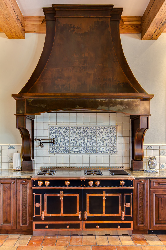 Inredning av ett medelhavsstil stort u-kök, med en rustik diskho, skåp i mörkt trä, blått stänkskydd, stänkskydd i terrakottakakel, integrerade vitvaror, klinkergolv i terrakotta och flerfärgat golv