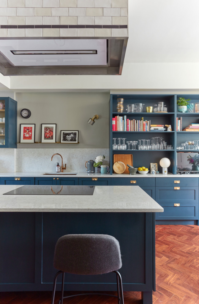 Immagine di un cucina con isola centrale vittoriano con lavello sottopiano, nessun'anta, ante blu, paraspruzzi bianco, pavimento in legno massello medio e top bianco