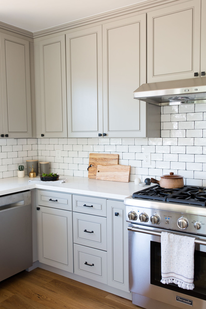 Mid-Century Küche mit Schrankfronten im Shaker-Stil, grauen Schränken, Quarzwerkstein-Arbeitsplatte, Küchenrückwand in Weiß, Rückwand aus Keramikfliesen, Küchengeräten aus Edelstahl und braunem Holzboden in San Francisco