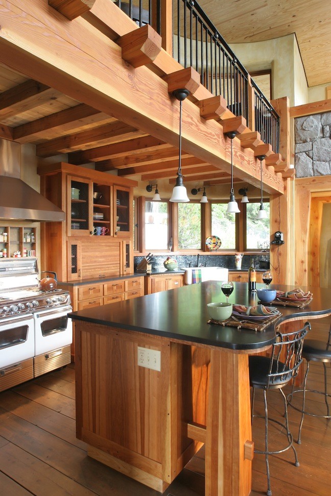 Foto på ett rustikt linjärt kök och matrum, med en rustik diskho, luckor med glaspanel, skåp i mellenmörkt trä, svart stänkskydd, stänkskydd i keramik, rostfria vitvaror, mellanmörkt trägolv, en köksö och bänkskiva i koppar