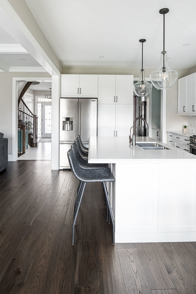 Idéer för ett modernt kök, med vita skåp, grått stänkskydd, mörkt trägolv, en köksö och brunt golv