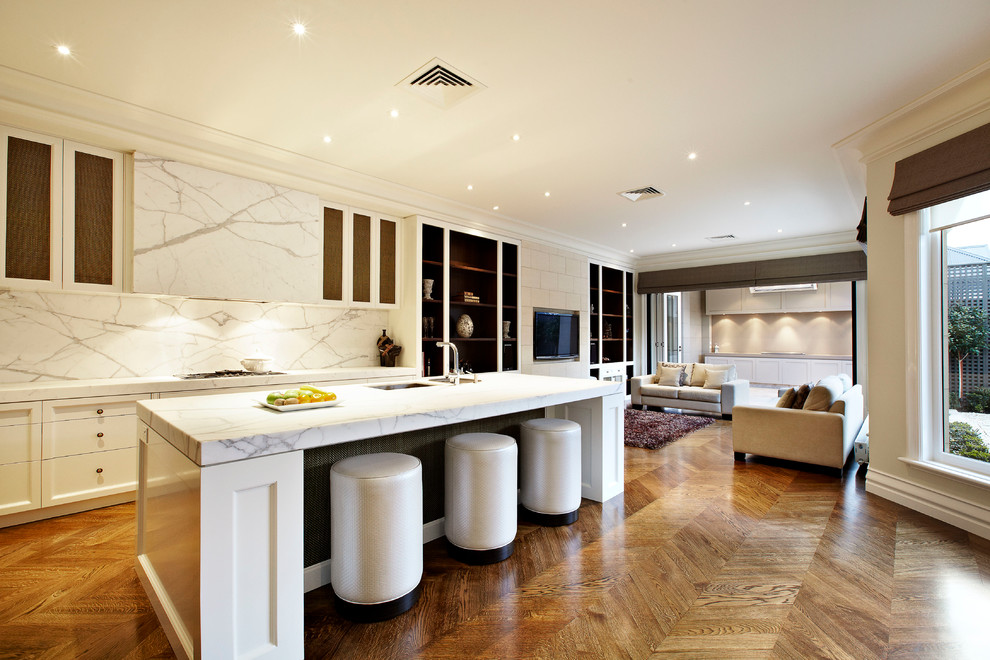 Large traditional galley open plan kitchen in Melbourne with a submerged sink, white cabinets, medium hardwood flooring and an island.