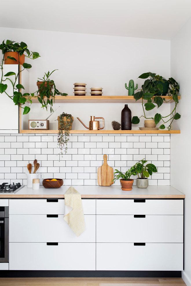 Inspiration for a mid-sized scandinavian light wood floor kitchen remodel in Melbourne with flat-panel cabinets, white cabinets, white backsplash and subway tile backsplash