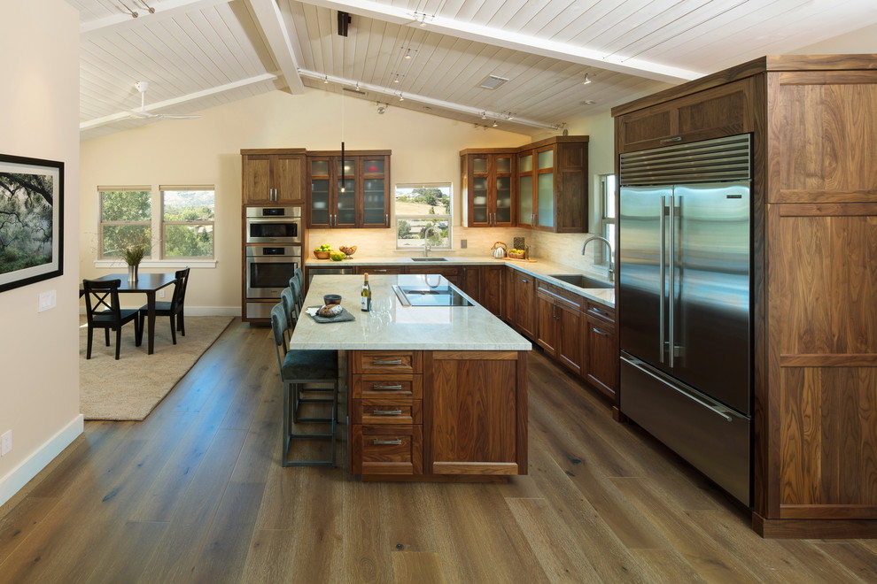 Inspiration for a mid-sized transitional l-shaped medium tone wood floor and brown floor open concept kitchen remodel in San Luis Obispo with an undermount sink, shaker cabinets, medium tone wood cabinets, quartzite countertops, beige backsplash, stone tile backsplash, stainless steel appliances and an island