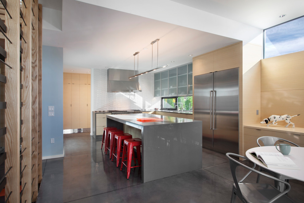 Foto di una cucina minimal con ante lisce, ante in legno chiaro, paraspruzzi bianco, elettrodomestici in acciaio inossidabile, pavimento in cemento, pavimento grigio e top grigio