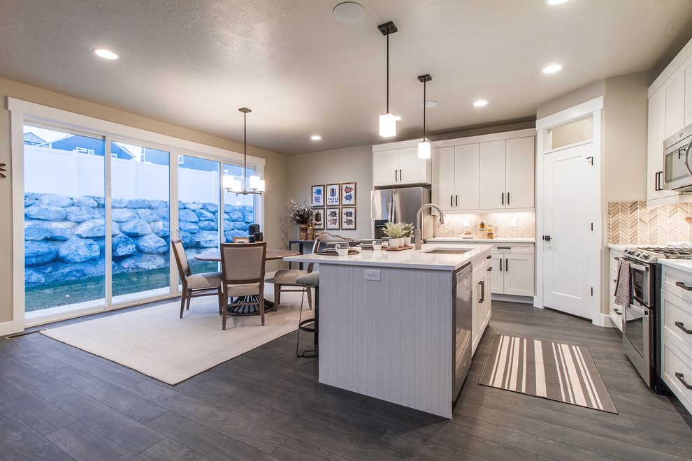Large traditional l-shaped open plan kitchen in Salt Lake City with a submerged sink, shaker cabinets, white cabinets, engineered stone countertops, brown splashback, mosaic tiled splashback, stainless steel appliances, dark hardwood flooring, an island and grey floors.