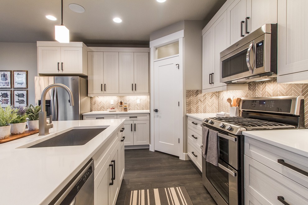 Example of a large transitional l-shaped dark wood floor and brown floor open concept kitchen design in Salt Lake City with an undermount sink, shaker cabinets, white cabinets, brown backsplash, stainless steel appliances, an island, quartz countertops and mosaic tile backsplash