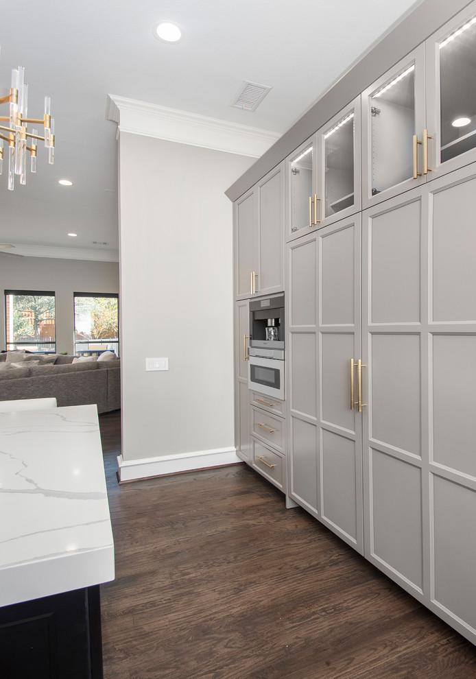 This is an example of a large contemporary u-shaped kitchen pantry in Dallas with a single-bowl sink, flat-panel cabinets, grey cabinets, engineered stone countertops, grey splashback, marble splashback, dark hardwood flooring, an island, brown floors, white worktops and integrated appliances.