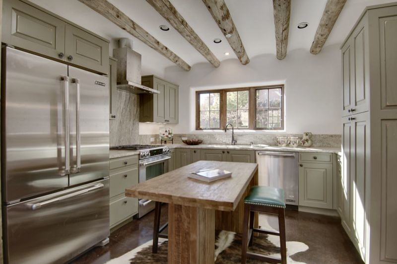 Foto på ett avskilt, mellanstort rustikt u-kök, med en undermonterad diskho, luckor med upphöjd panel, gröna skåp, granitbänkskiva, grått stänkskydd, stänkskydd i sten, rostfria vitvaror, betonggolv, en köksö och brunt golv
