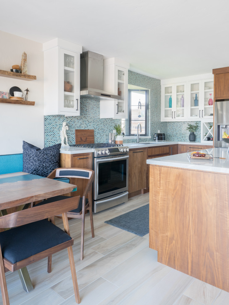 Foto på ett funkis vit kök, med en undermonterad diskho, släta luckor, skåp i mellenmörkt trä, blått stänkskydd, stänkskydd i mosaik, rostfria vitvaror och beiget golv