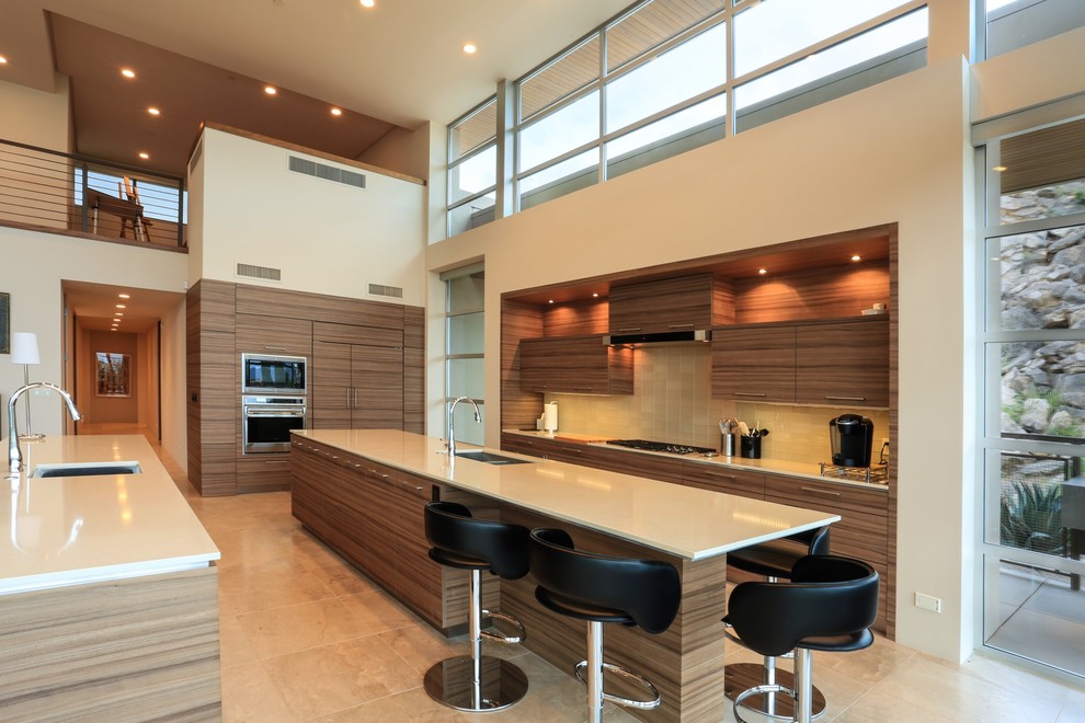 Contemporary kitchen in Phoenix with a submerged sink, flat-panel cabinets, medium wood cabinets, beige splashback, glass tiled splashback, integrated appliances and multiple islands.