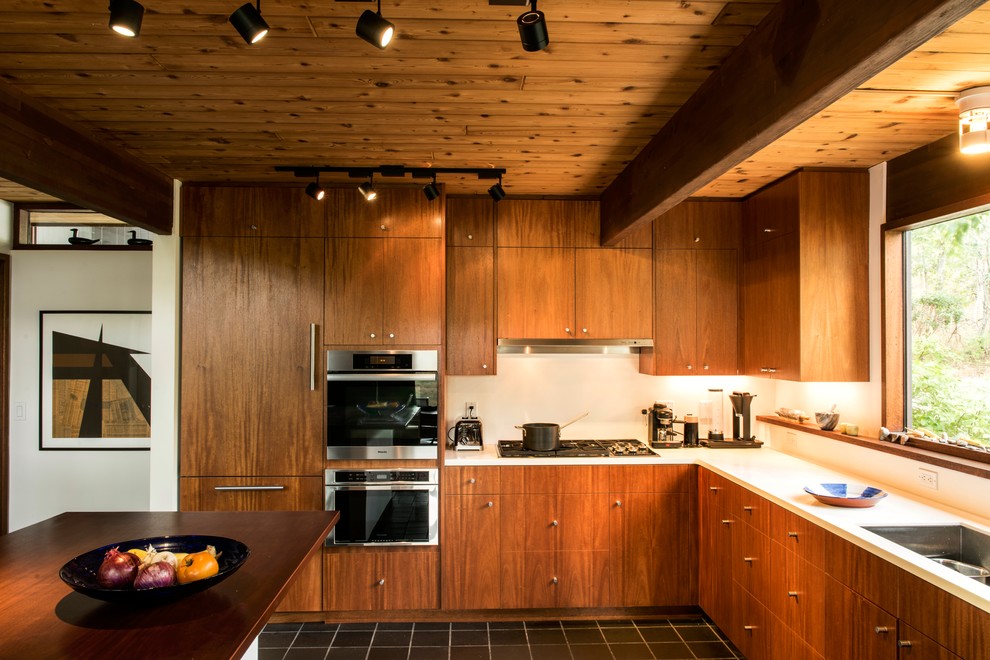Aménagement d'une cuisine contemporaine en bois brun avec un évier encastré, un placard à porte plane, une crédence blanche, un électroménager en acier inoxydable et îlot.