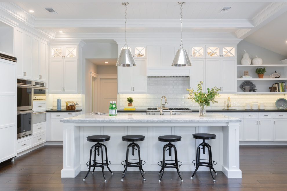 Inspiration for a traditional kitchen in Los Angeles with shaker cabinets, white cabinets, white splashback, metro tiled splashback, stainless steel appliances, medium hardwood flooring and an island.