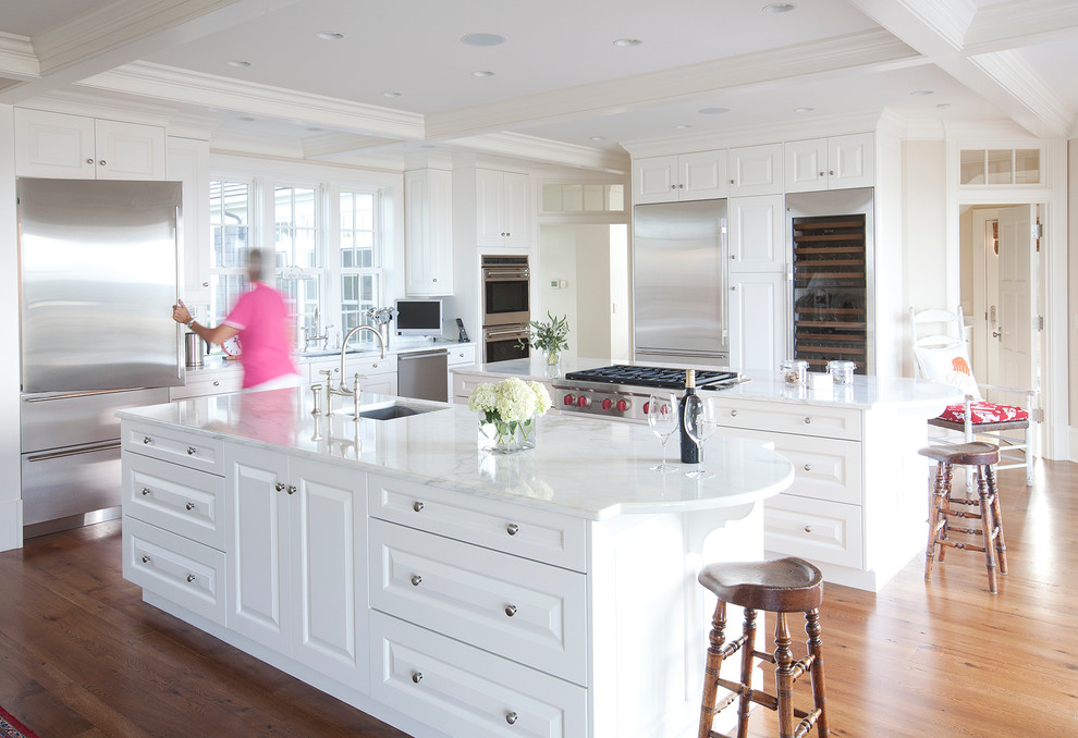Eat-in kitchen - large traditional medium tone wood floor eat-in kitchen idea in Boston with an undermount sink, raised-panel cabinets, white cabinets, marble countertops, white backsplash, stainless steel appliances and two islands