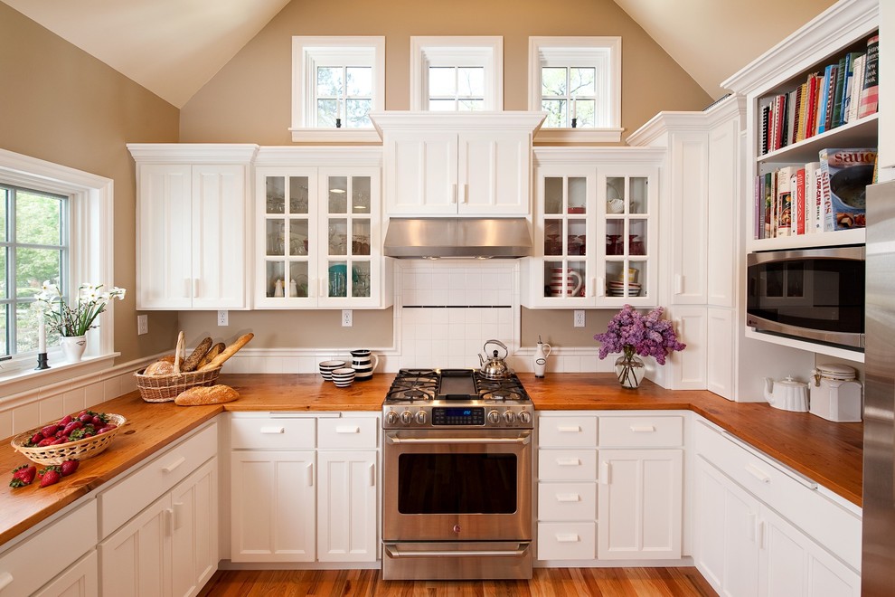 Inspiration for a mid-sized timeless u-shaped medium tone wood floor enclosed kitchen remodel in Portland with stainless steel appliances, wood countertops, shaker cabinets, white cabinets, white backsplash, no island and ceramic backsplash