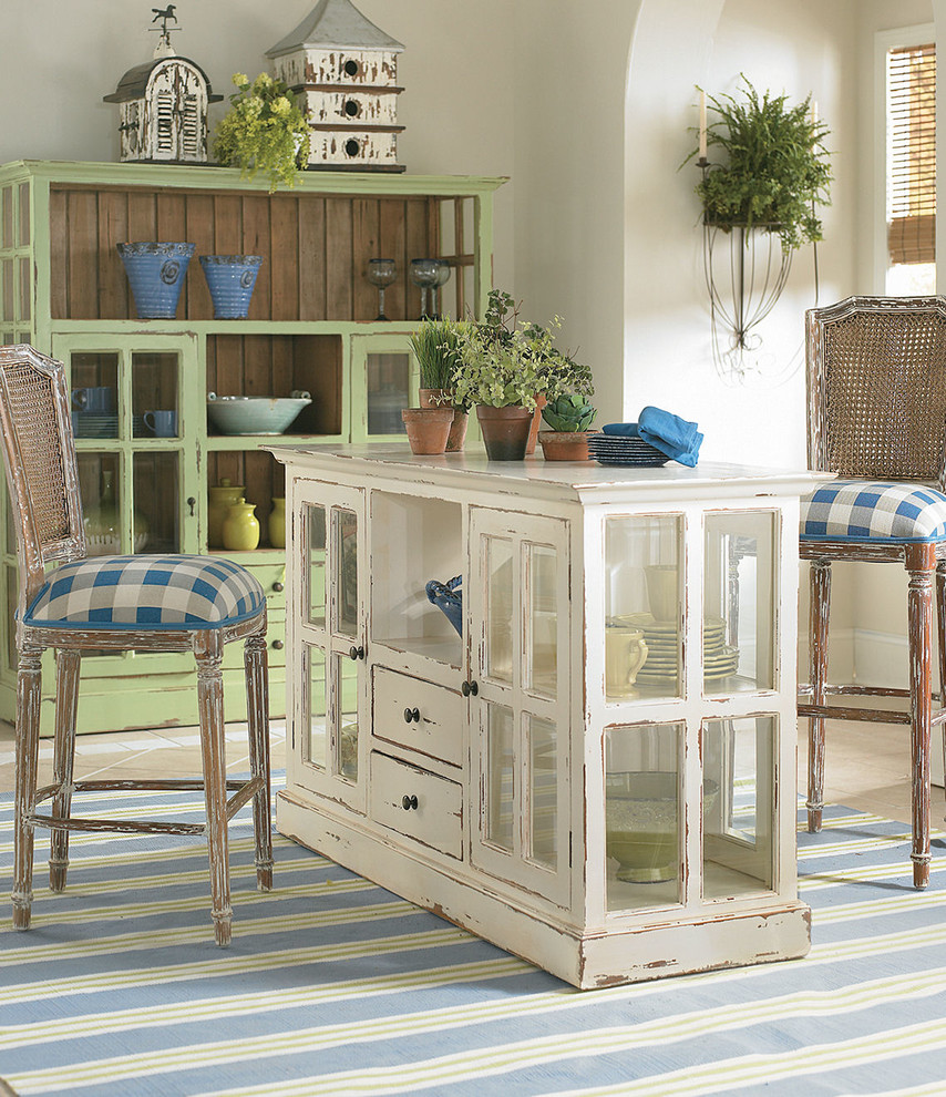 This is an example of a medium sized country kitchen/diner in Charlotte with glass-front cabinets, distressed cabinets, wood worktops and beige floors.