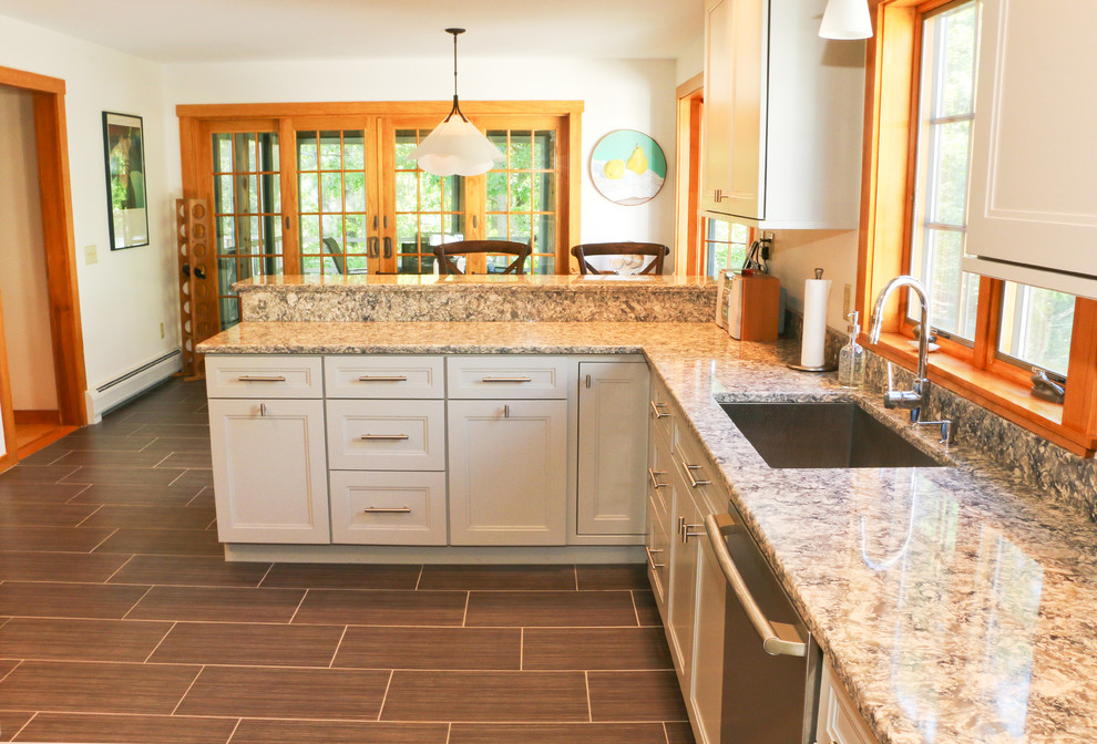 Modern inredning av ett kök, med en nedsänkt diskho, grå skåp, marmorbänkskiva, vitt stänkskydd och rostfria vitvaror