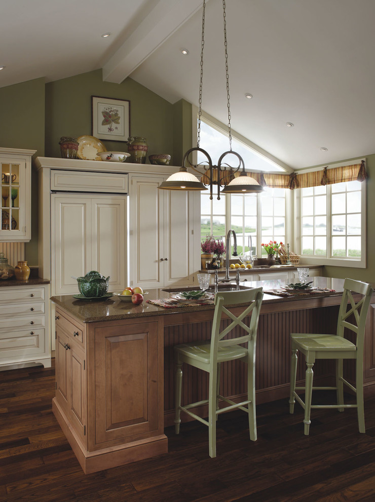 Inredning av ett klassiskt stort kök, med en undermonterad diskho, luckor med upphöjd panel, vita skåp, rostfria vitvaror, mellanmörkt trägolv, en köksö och brunt golv