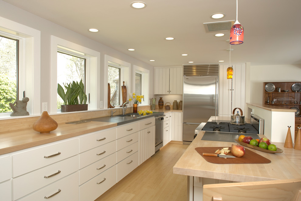 サンフランシスコにあるコンテンポラリースタイルのおしゃれなキッチン (白いキャビネット、木材カウンター、シルバーの調理設備) の写真