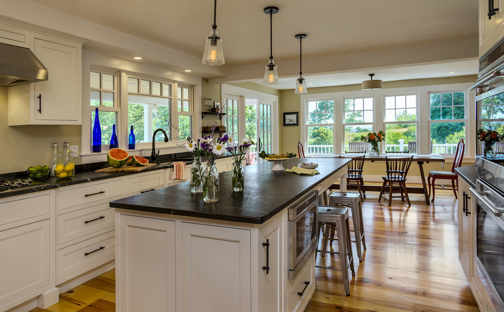 Inspiration for a mid-sized timeless galley medium tone wood floor eat-in kitchen remodel in Boston with an undermount sink, beaded inset cabinets, white cabinets, soapstone countertops, stainless steel appliances, an island and black backsplash