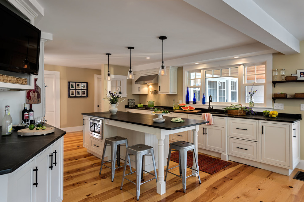 Zweizeilige, Mittelgroße Klassische Küche mit Unterbauwaschbecken, Kassettenfronten, weißen Schränken, Speckstein-Arbeitsplatte, braunem Holzboden und Kücheninsel in Boston